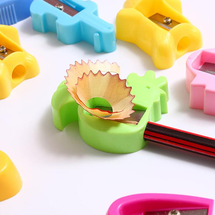 Close-up of green single-hole pencil sharpener with exposed blade and shavings