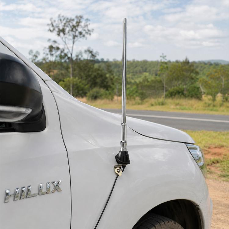 Car radio antenna mounted on a light gray pickup fender with black cable