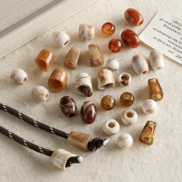 Large-hole acrylic beads in mixed white and amber marbled tones, assorted shapes
