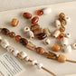 Large-hole acrylic beads, marbled amber and white, strung along a beaded cord