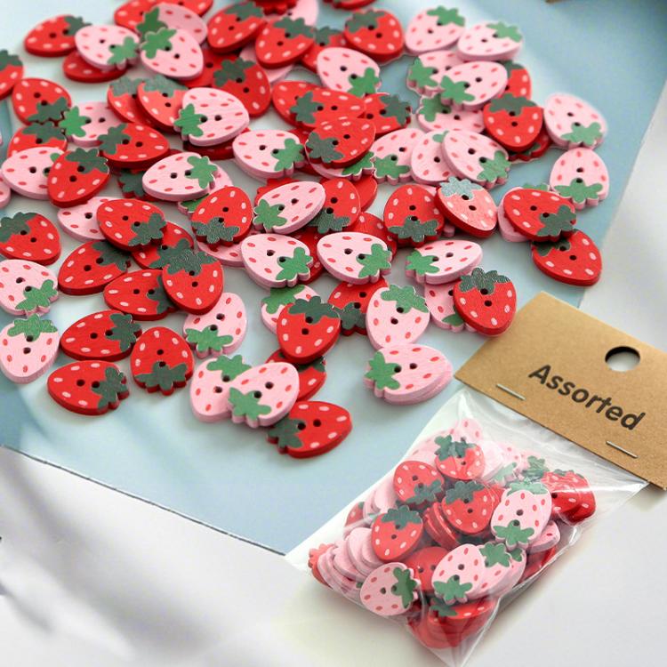 Close-up of strawberry-shaped wooden buttons in red, pink, and green leaf details