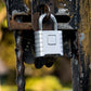 Silver combination padlock locked onto a dark metal gate frame