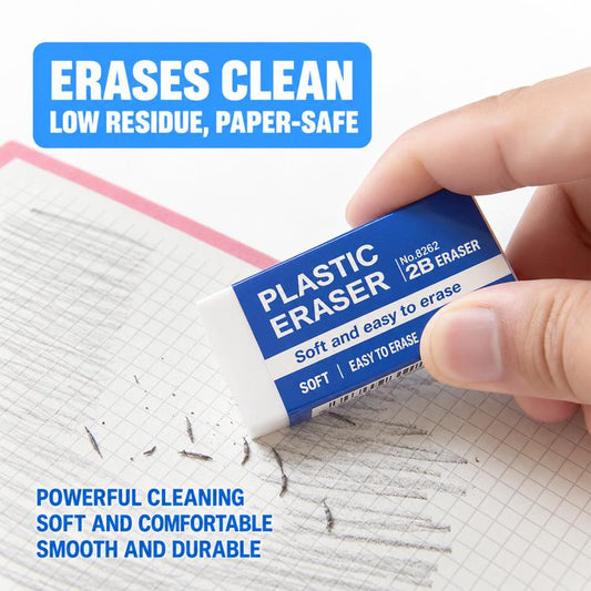 Hand holding a white 2B eraser on graph paper, blue label on top.