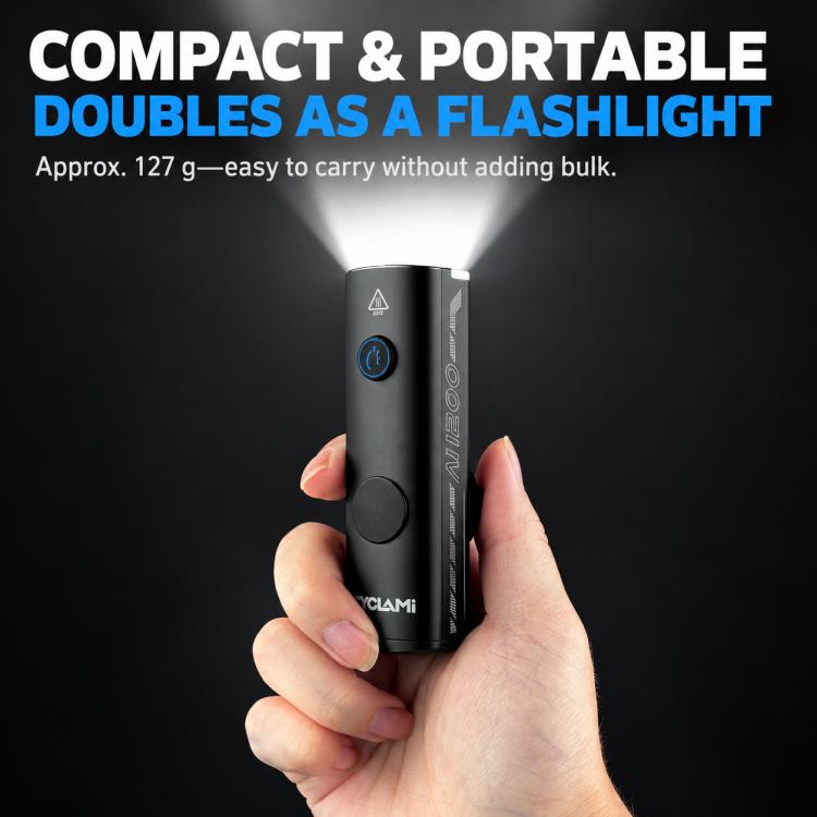 Compact CYCLAMi flashlight-style bike light held in hand, black metal body