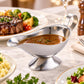 Stainless steel sauce boat with spout and handle, filled with brown gravy