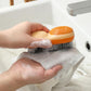Orange double-sided laundry brush with foam scrubbing white fabric in sink