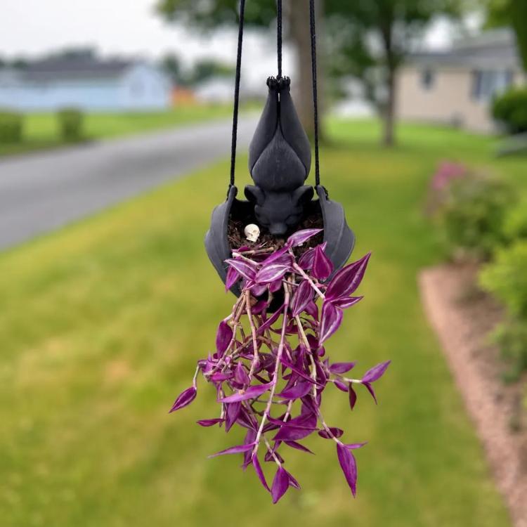 Hanging bat-shaped plant pot with purple trailing foliage and hanging cord