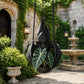 Hanging bat-shaped plant pot with black bat design and green leafy plants