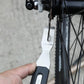 Spoke/tool wrench held near bicycle wheel spokes for adjustment