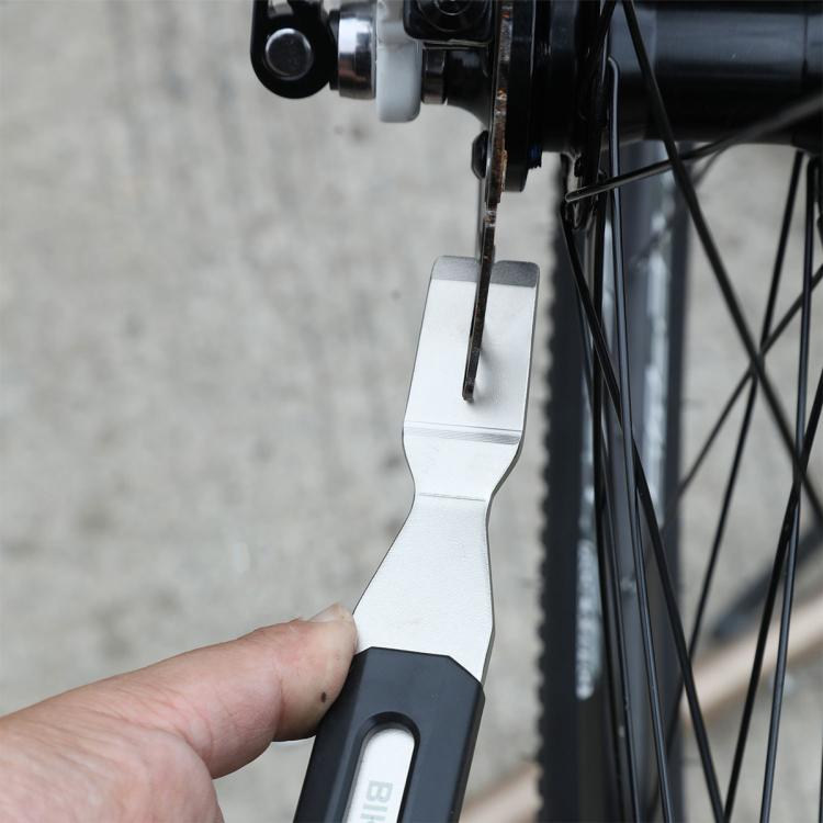 Spoke/tool wrench held near bicycle wheel spokes for adjustment