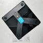 Black smart body fat scale with textured grip feet and LCD screen