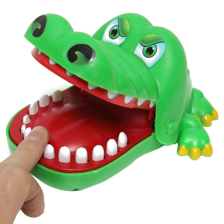 Green crocodile bite toy with open jaws and white teeth; hand pressing from side