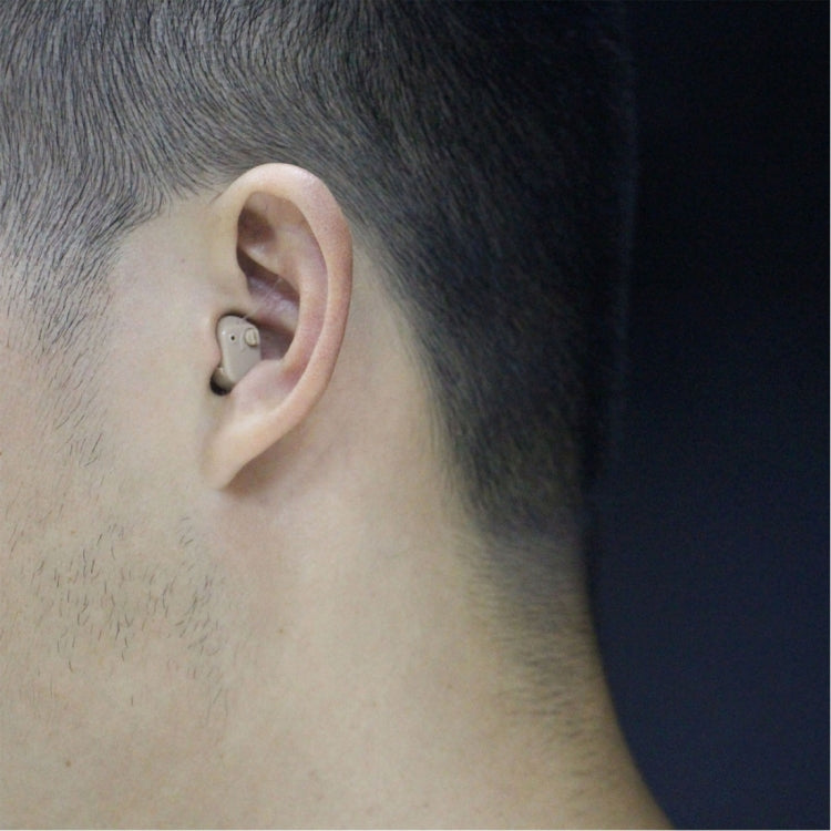Beige in-ear hearing aid worn behind ear on model