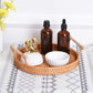 Braided snack basket tray with wooden handles holding amber bottles and white ribbed bowls