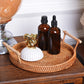 Braided snack basket tray with wooden handles, amber bottles and white ribbed bowls with gold ornament