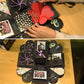 Person arranging a black photo explosion album on a wooden table with heart and butterfly covers