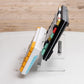 Transparent acrylic keyboard stand with metal pins, propped beside keycaps