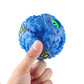 Blue bumpy chew ball held in hand, green ring openings and yellow paw print detail