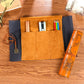 Tan multi-compartment pencil bag with dark sleeve and orange rolled case