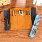 Tan pencil bag with multiple pen pockets, dark side sleeve, blue rolled case