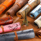 Assorted rolled pencil bags with compass map prints in orange, brown, pink, blue, and gray