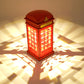 Red lit phone booth bedside lamp with glowing grid windows and crown top.