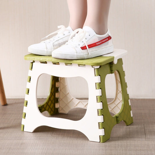 Green and white plastic folding stool with carry cutout top, standing with open legs