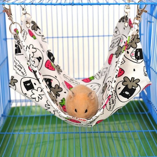 Pet hammock bed with cream canvas and colorful animal prints, holding a small hamster