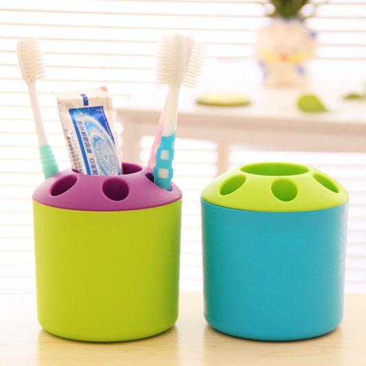 Two round cup holders with open slots, purple and green with toothbrushes
