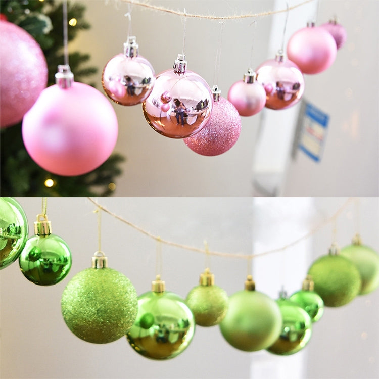 Pink and green plastic Christmas ornament balls on a hanging string with hooks.