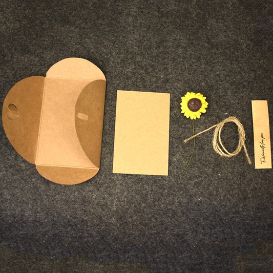 Assorted kraft greeting cards with dry flowers, twine, and small tags laid out