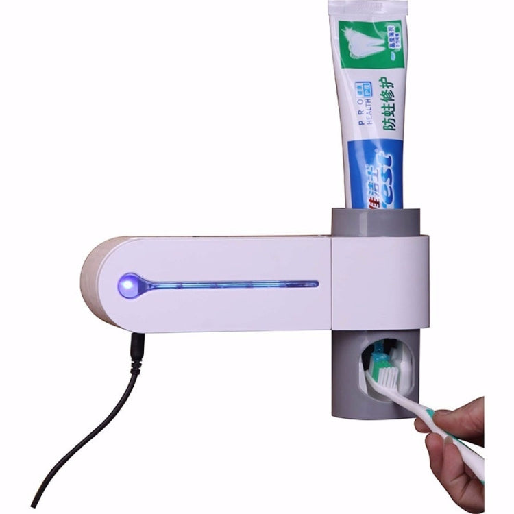 Automatic toothpaste dispenser with UV indicator light bar and tube holder above toothbrush slot