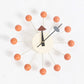 Wall clock with orange ball arms, cream face, black hands with gray secondary arm