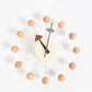 Wall clock with peach ball arms, cream face, black hands and brown triangular marker
