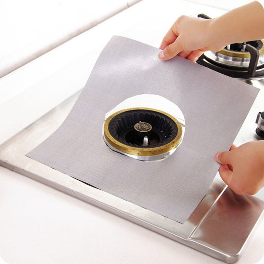Square silver stovetop protective cleaning pad with burner opening, held above a gas stove
