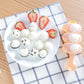 Peach spoon-shaped sushi rice ball mold holding rice balls with strawberry slices