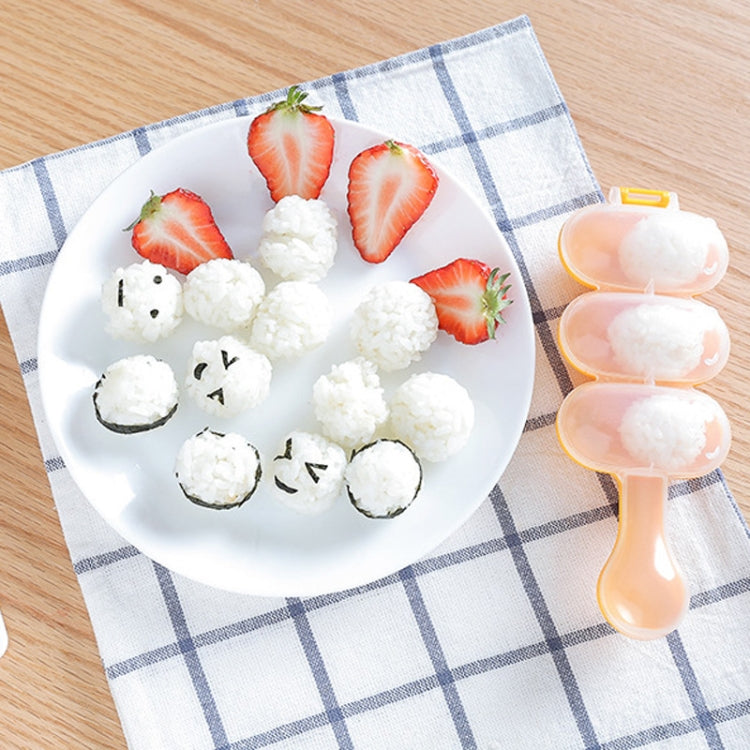 Peach spoon-shaped sushi rice ball mold holding rice balls with strawberry slices