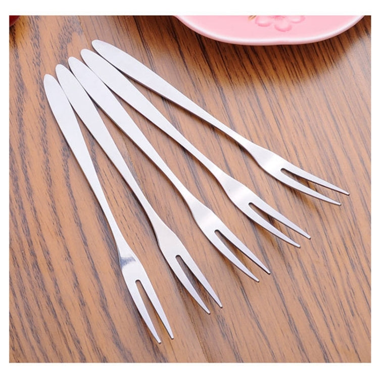 Stainless steel fruit fork set, multiple forks fanned out on wooden surface