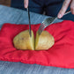 Red potato cooker bag with two potatoes and a knife over the opening