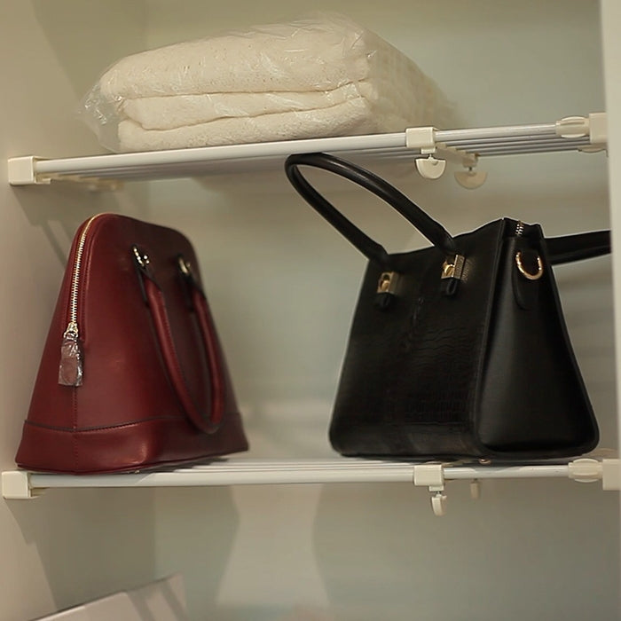 White cabinet shelf rack with rails and hooks displaying two handbags