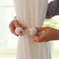 Pair of pearl magnetic curtain tiebacks with braided strap on sheer curtain