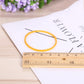 Yellow elastic rubber band loop shown with a ruler and white card
