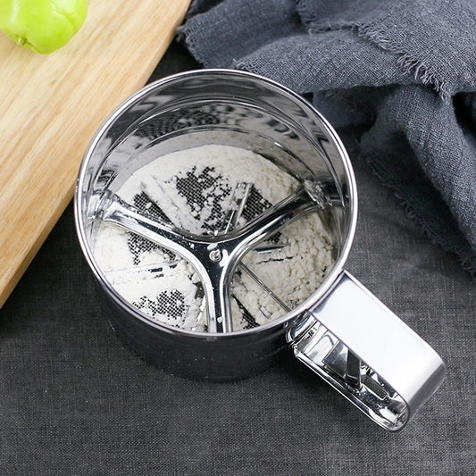 Stainless steel mesh sifter drum with handle, filled with flour (top view)