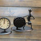 Retro small alarm clock showing back of black circular mechanism on metal stand