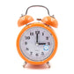 Orange metal twin bell alarm clock with analog face, quartz text, and blue night-light icon.