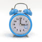 Blue metal twin bell alarm clock with analog face, quartz text, and blue night-light icon.