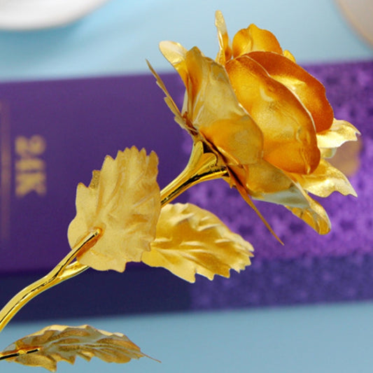 Artificial golden rose with gold-foil leaves on a gold stem.