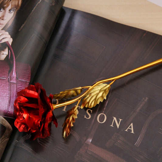 Artificial red rose with gold-foil leaves on a gold stem decoration.