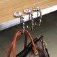 Chrome folding bag hanger with round disc top and hook clip holding a bag loop
