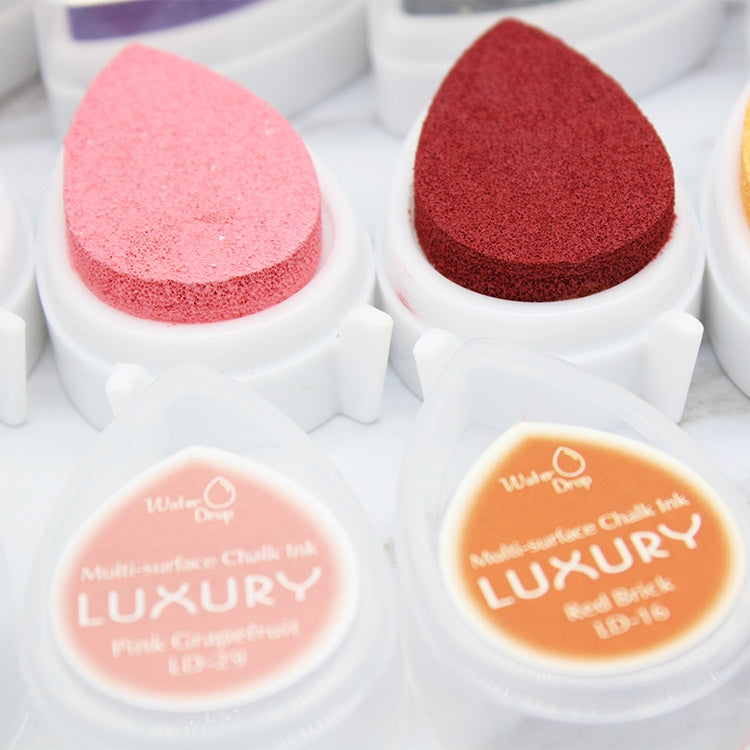 Close-up of pink and red droplet-shaped ink stamp pads with round color lids